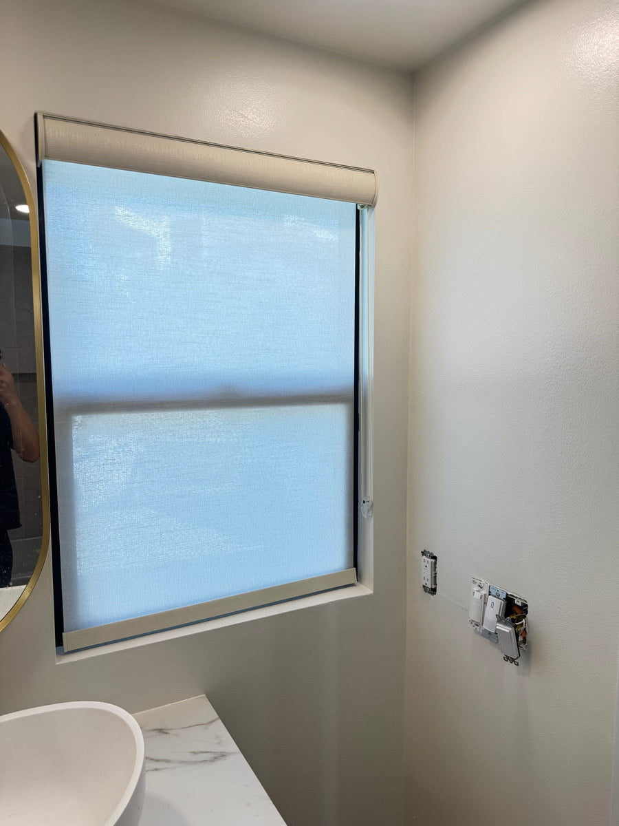 Neutral roller shade inside a small window recess above a stone counter