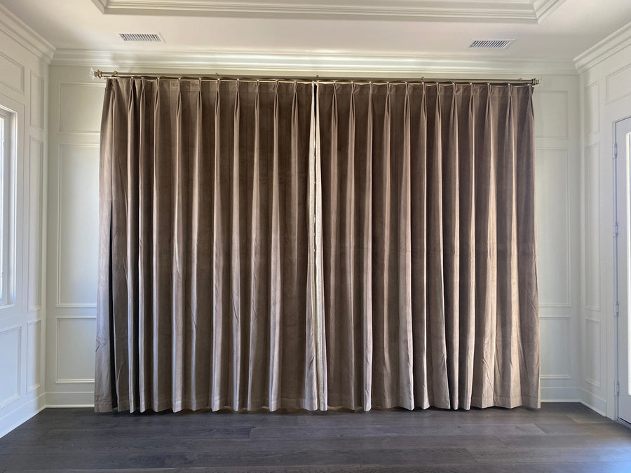 Wider view of the pinch-pleat drapery against pale wall paneling and dark oak flooring