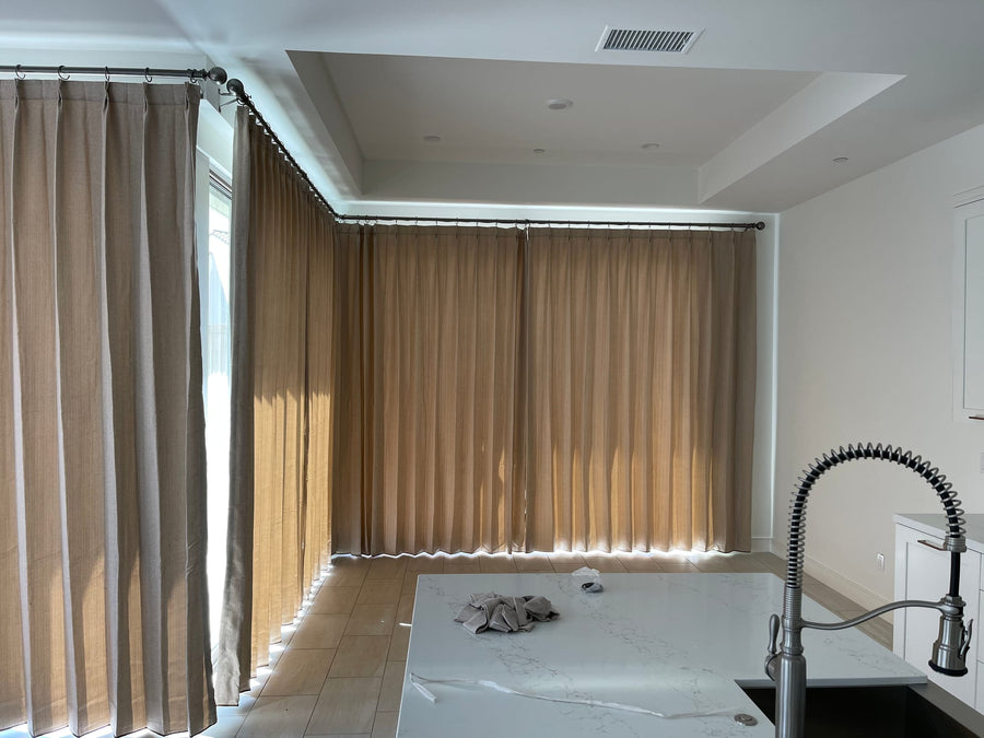 Drapery running around a corner window wall beside the kitchen island