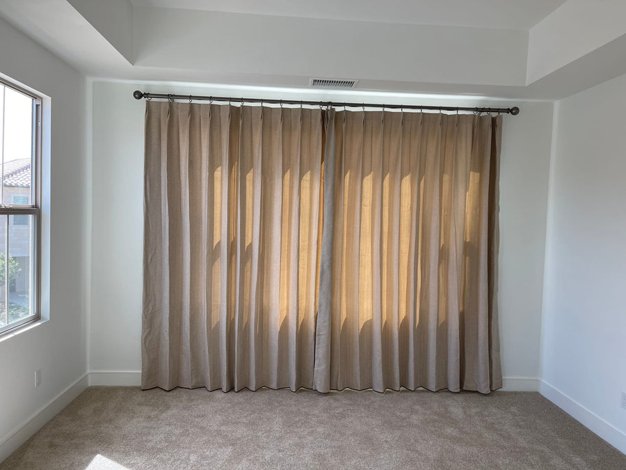 Floor-length drapery in a bedroom with a tray ceiling and side window