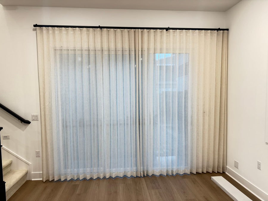 Sheer drapery panels filtering daylight at a slider next to the stair landing