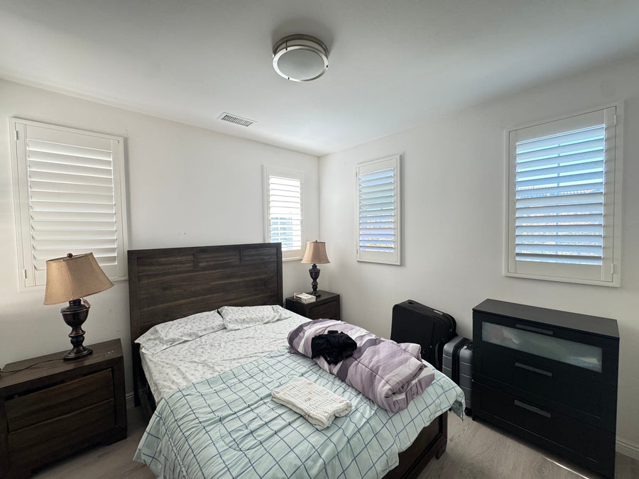 Bedroom with four differently sized windows unified by white shutters