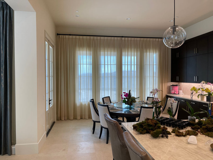 Dining area windows dressed in the same pleated sheers, drawn to floor length