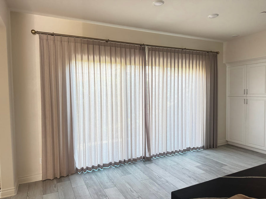Angled view of the living room window wall with layered sheers and side panels