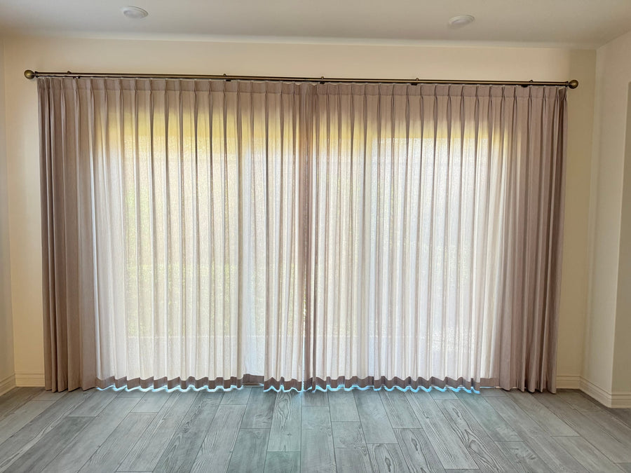 Full-width sheers on an antique brass rod, hems breaking above pale oak flooring