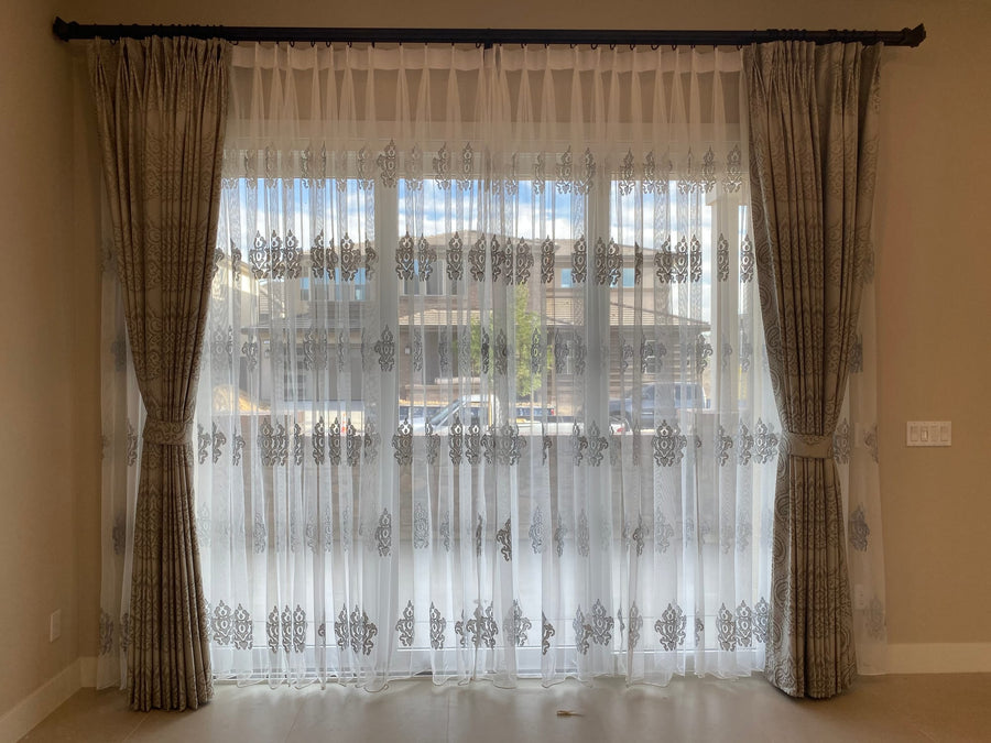 Sheer panel centred on a sliding door with taupe patterned side panels and tiebacks