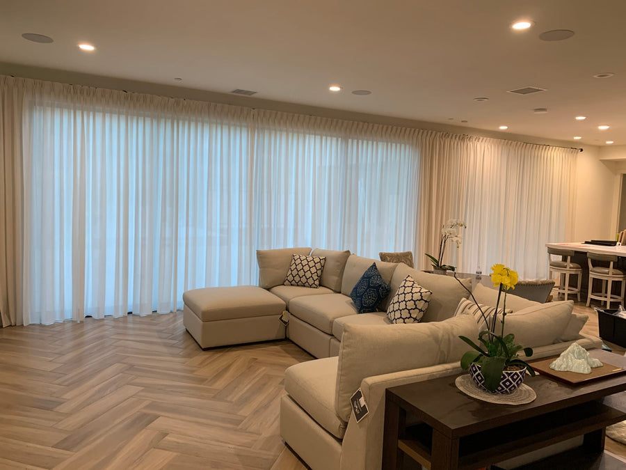 White sheer drapery on a ceiling track wrapping an open-plan living room in daylight