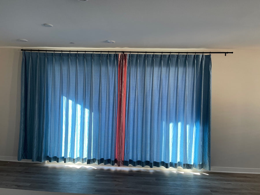 Full view of the drapery panels closed, daylight filtering through the textured blue fabric