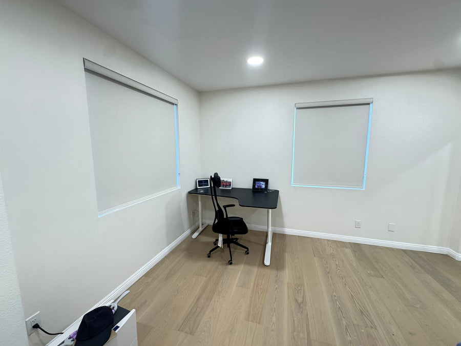 Study corner with two blackout roller shades lowered on adjacent walls