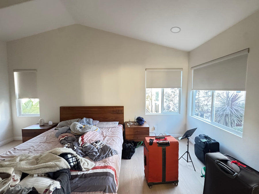 Bedroom under a vaulted ceiling with roller shades at three window heights
