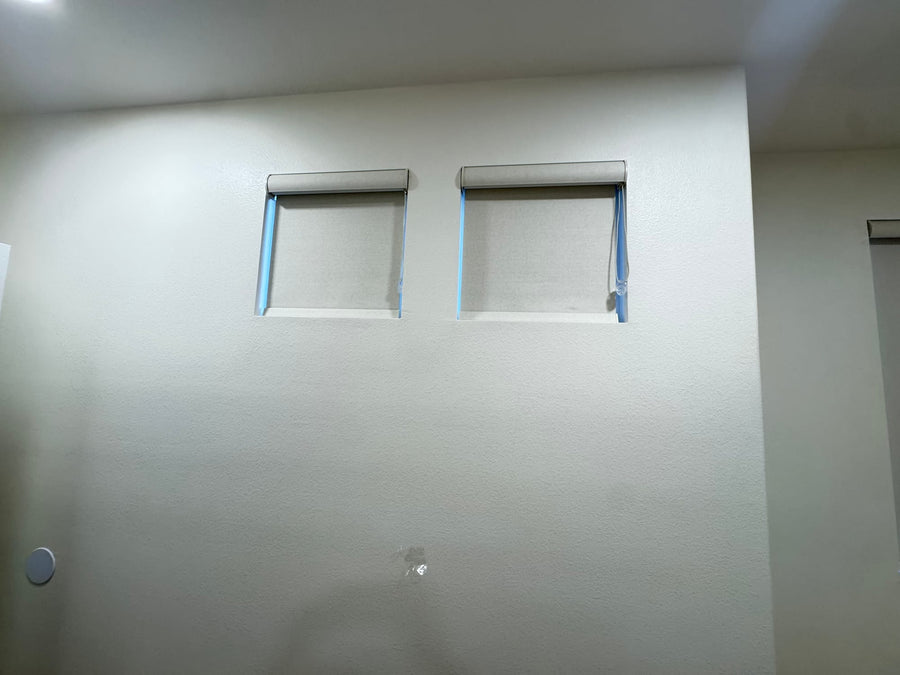 Two small high windows fitted with custom-sized roller shades