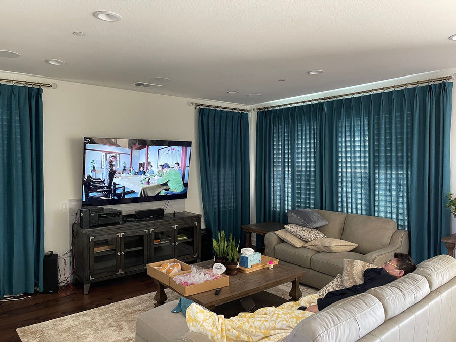 Teal drapery framing living room windows, light filtering through