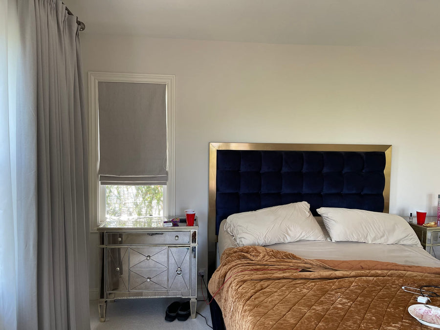 Solid grey Vignette shade beside floor-length drapery in a bedroom