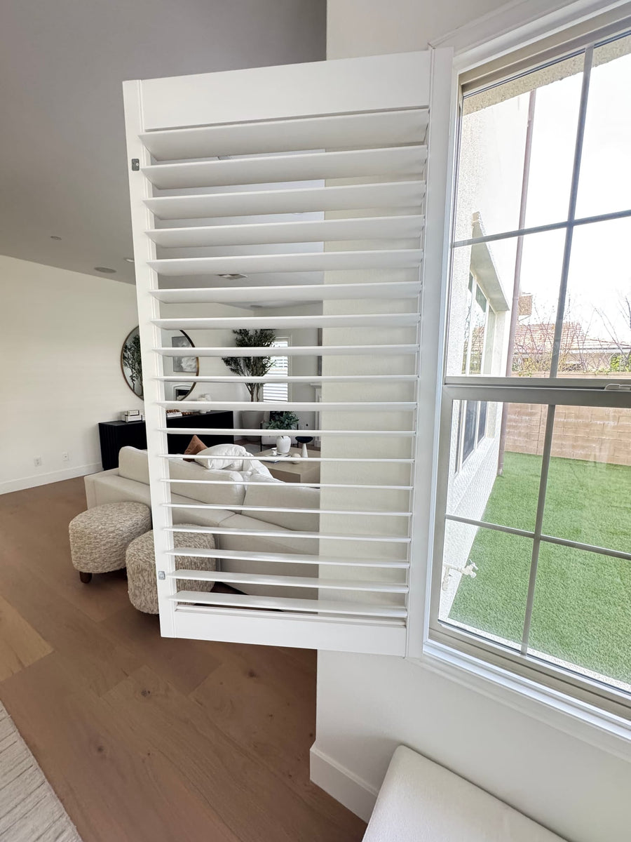 Hinged shutter panel swung open beside a rear window overlooking the yard