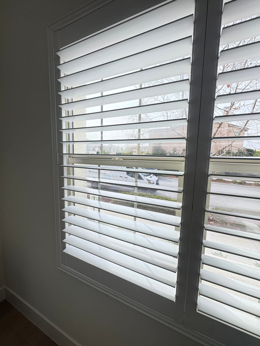Close view of white shutter louvers filtering street-side daylight