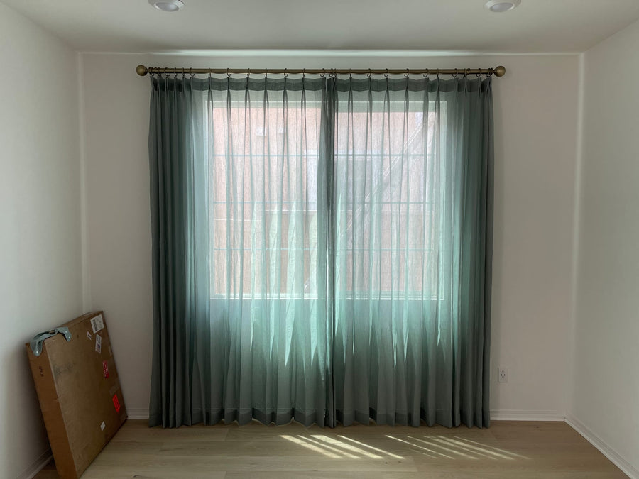 Pinch-pleat sheer panels filtering daylight in an empty room