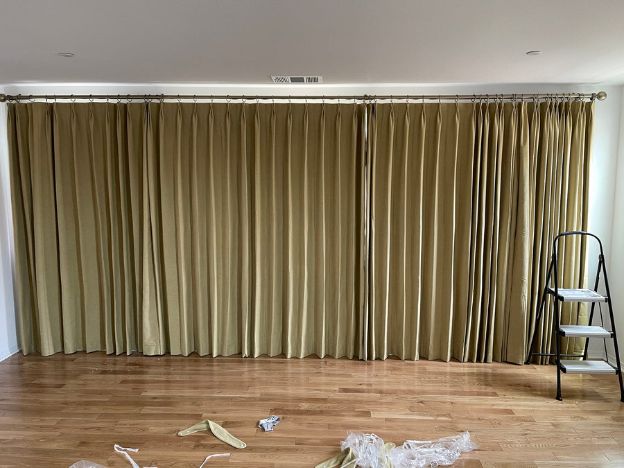 Olive drapery panels drawn closed across a full wall