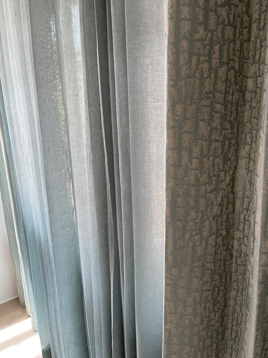 Close view of sheer linen layered against a textured drapery panel